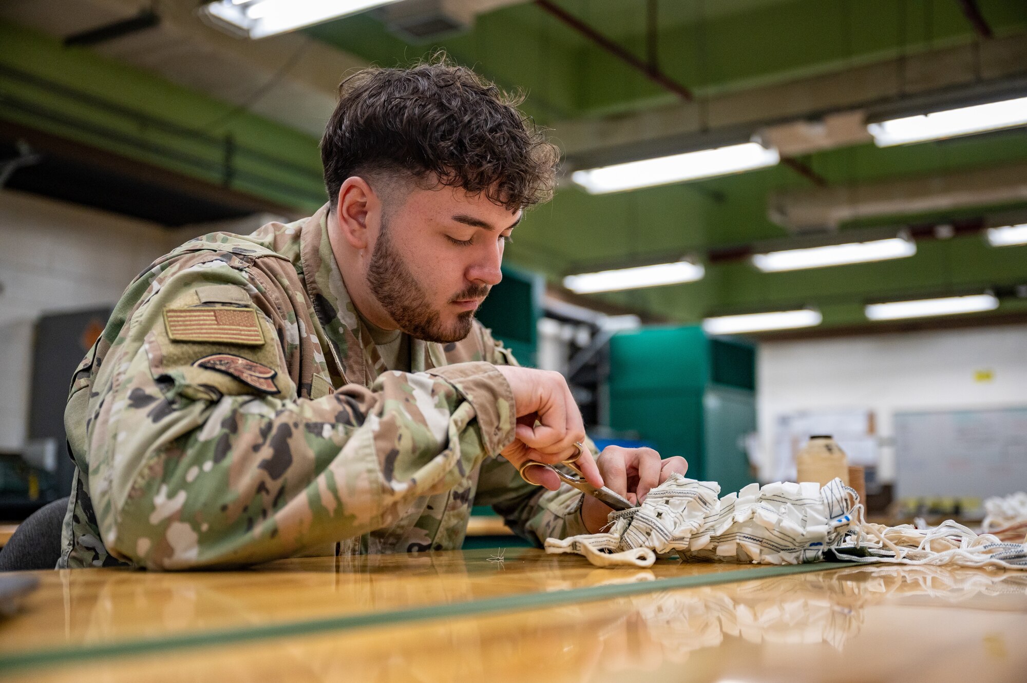 U.S. Air Force Staff Sgt. Vicente Olvera, 51st Operations Support Squadron aircrew flight equipment main shop noncommissioned officer in charge, rigs a drogue parachute at Osan Air Base, Republic of Korea, Sept. 25, 2023. AFE specialists conduct routine inspections and maintenance on flight equipment to guarantee the 25th and 36th Fighter Squadrons are always ready to execute the fight tonight mission. (U.S. Air Force photo by Staff Sgt. Thomas Sjoberg)