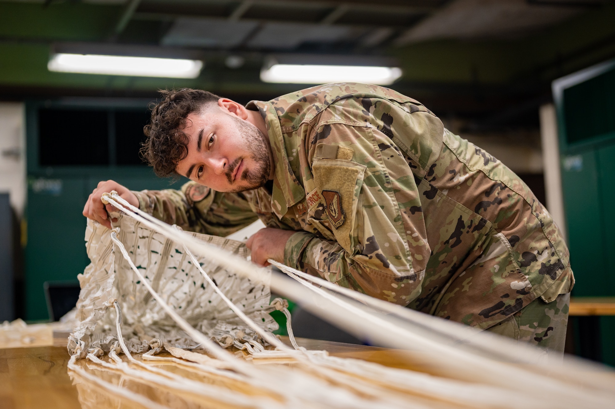 U.S. Air Force Staff Sgt. Vicente Olvera, 51st Operations Support Squadron aircrew flight equipment main shop noncommissioned officer in charge, conducts a routine inspection on a drogue parachute at Osan Air Base, Republic of Korea, Sept. 25, 2023. A drogue parachute stabilizes and slows down the ejection seat during a pilot’s descent. By maintaining these parachutes, AFE specialists ensure the combat capability and safety of 51st Fighter Wing pilots. (U.S. Air Force photo by Staff Sgt. Thomas Sjoberg)