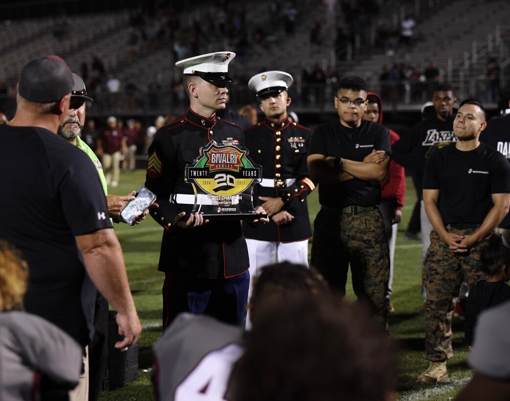 U.S. Marine Corps Sgt. Robert Chapman, center, a recruiter with Recruiting Station Richmond, 4th Marine Corps District, presents a medal to the Thomas Dale Highschool after winning a Great American Rivalry Series game in Chester, Virginia, Aug. 31, 2023.  Recruiters conducted a pull-up challenge, passed out t-shirts and presented awards to the athletes to further connect with the local community and raise Marine Corps awareness. (U.S. Marine Corps photo by Sgt. Godfrey Ampong)