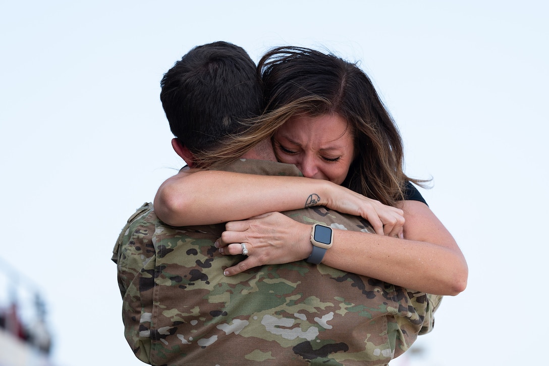 An airman in uniform hugs another person.