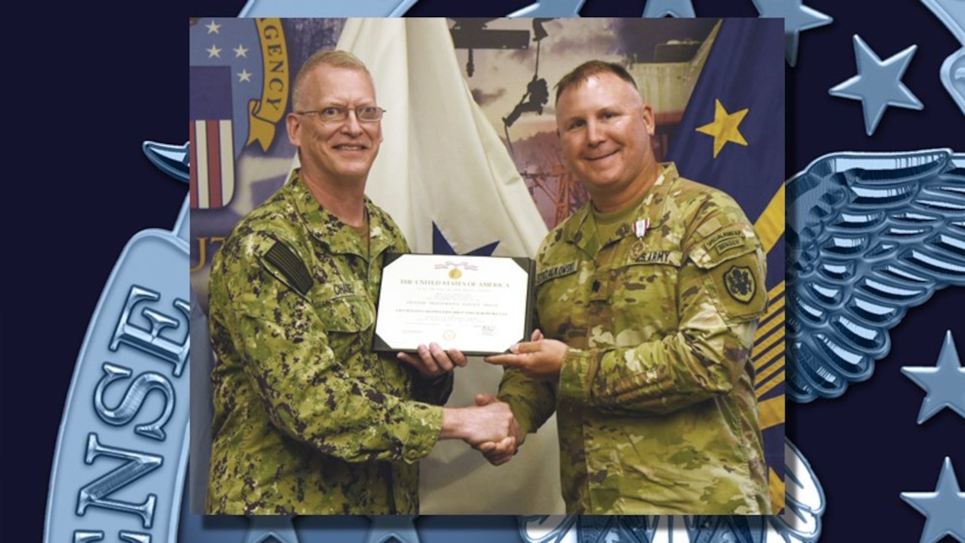Two men in military uniform standing and holding a certificate between them