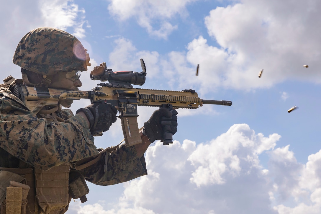 Ammunition flies to the right as a Marine fires a weapon.