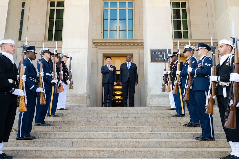 A U.S. and a Japanese defense leader stand at the top of the Pentagon steps during a ceremony.