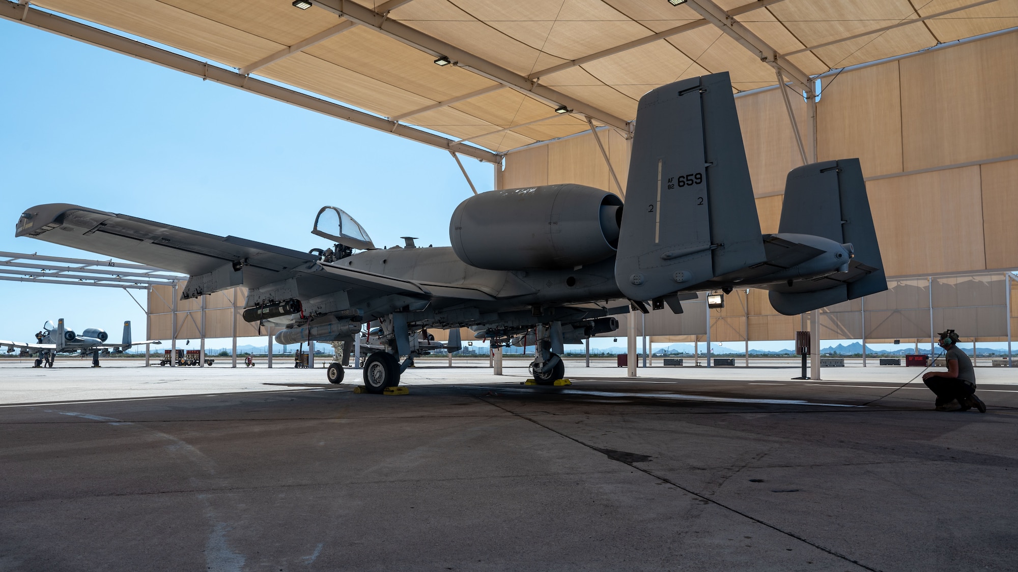 U.S. Air Force Airman 1st Class Sergeant Tanner, 357th Fighter Generation Squadron crew chief, communicates via communication cord by an A-10C Thunderbolt II aircraft on Davis-Monthan Air Force Base, Ariz., Oct 3, 2023. The A-10 was the first aircraft specifically designed for close air support of ground forces. (U.S. Air Force photo by Airman 1st Class Robert Allen Cooke III)