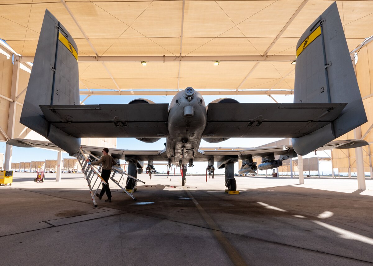 U.S. Air Force Senior Airman Carter Wedding, 357th Fighter Generation Squadron crew chief, carries a ladder under the wing of an A-10C Thunderbolt II aircraft at Davis-Monthan Air Force Base, Ariz., Oct. 3, 2023. Wedding climbed the ladder to work on the plane before they it was cleared for takeoff. (U.S. Air Force photo by Airman 1st Class Robert Allen Cooke III)