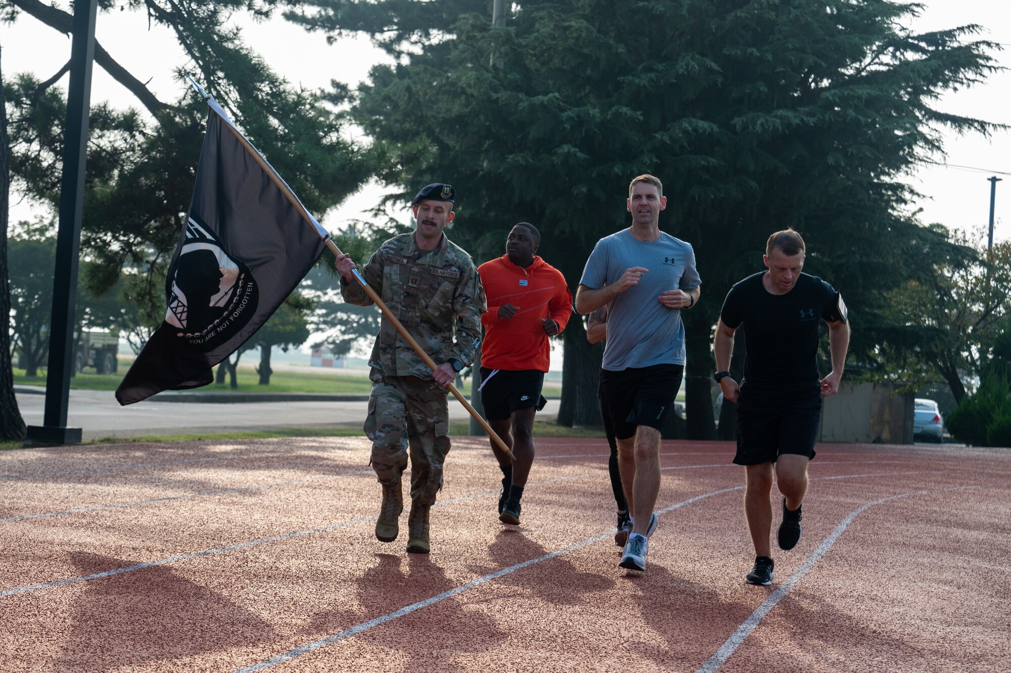 8th Fighter Wing leadership runs on a track during the 24-hour POW-MIA remembrance run.