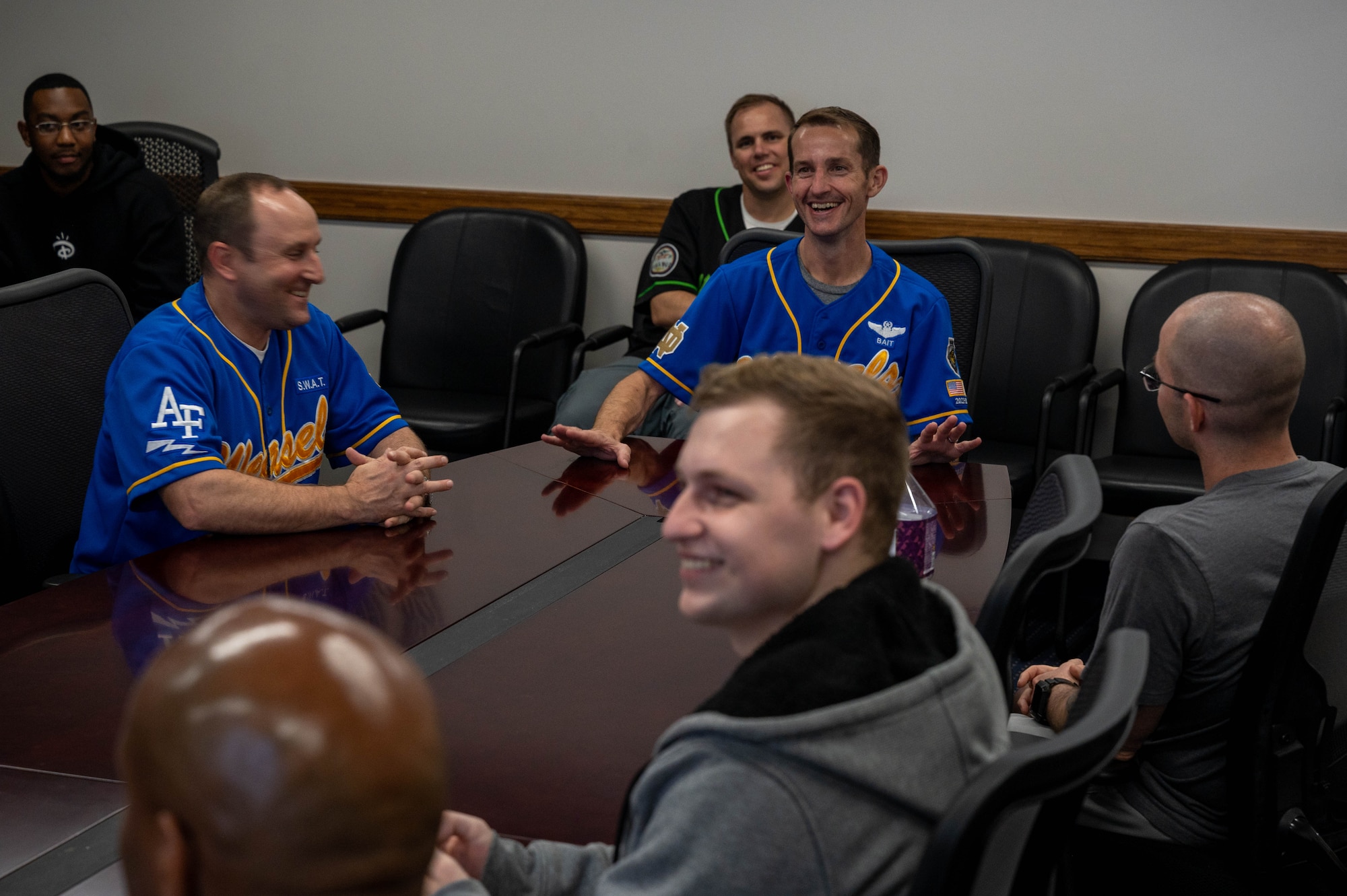 A group of people sitting around a conference table laughing.