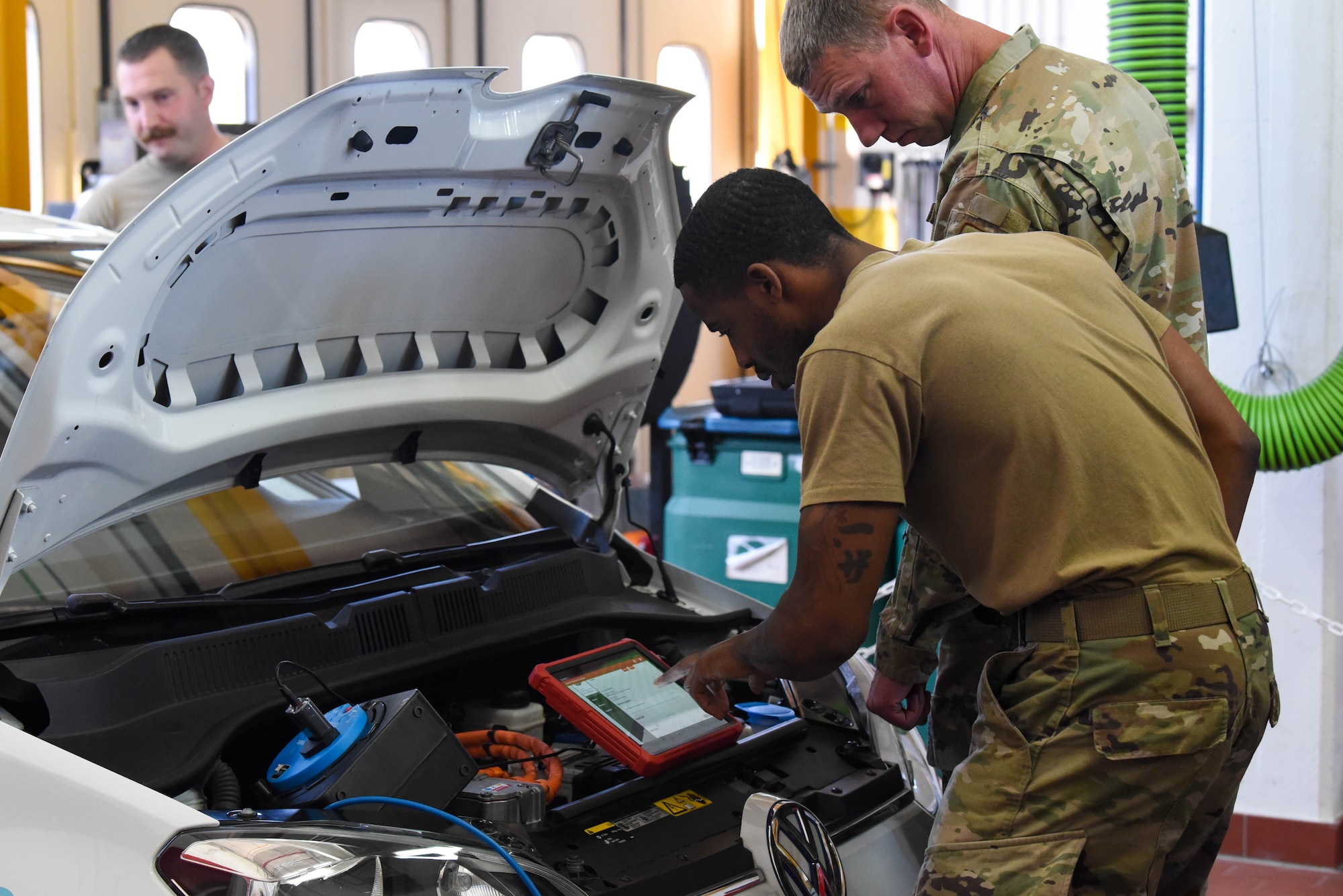 Service members look at car engine.