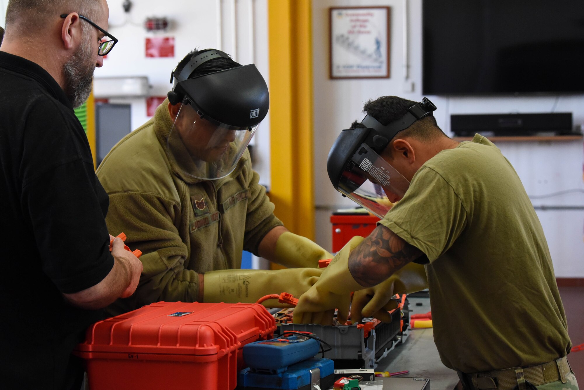 Service members work on car engine.