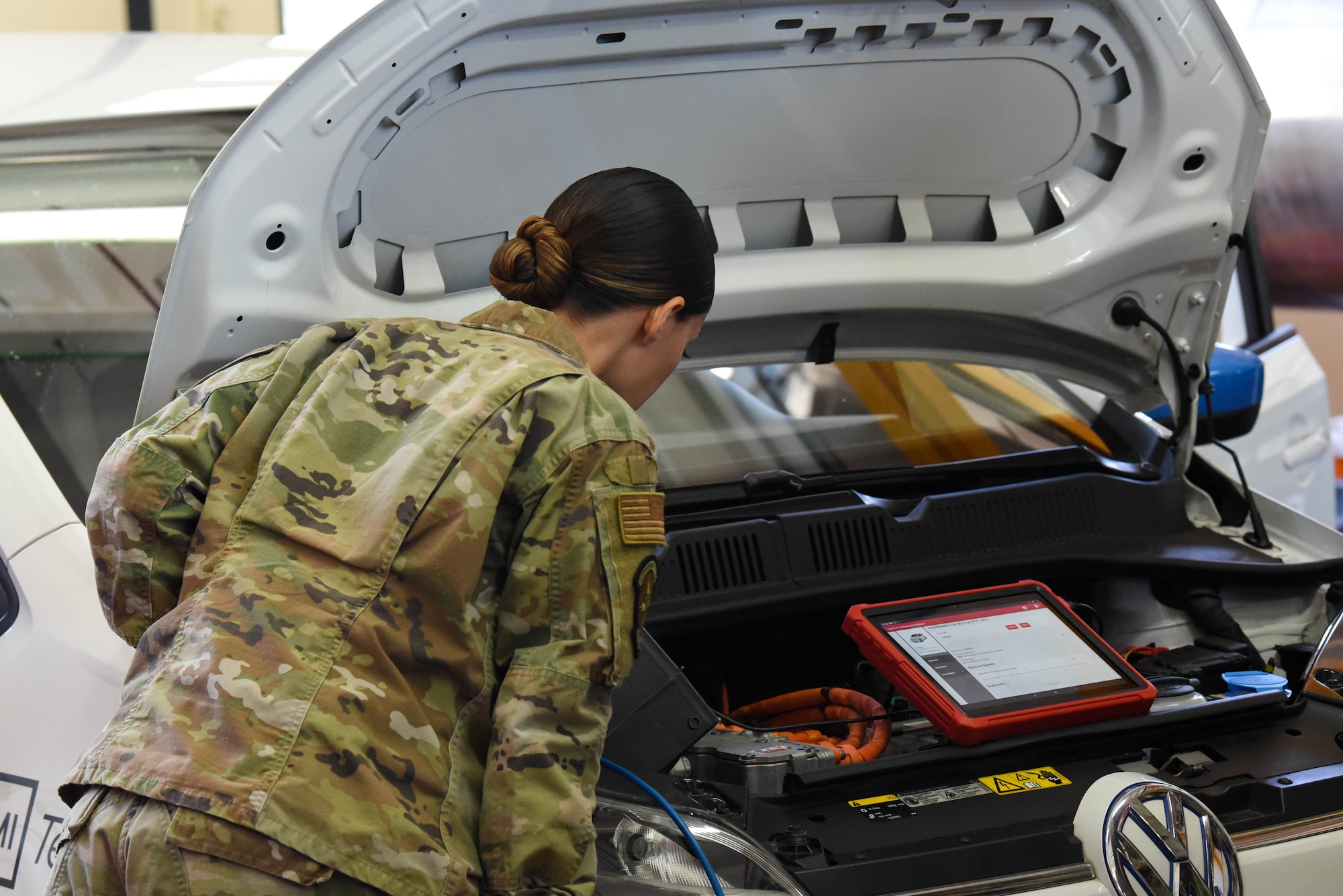 Service member looks at a car engine.