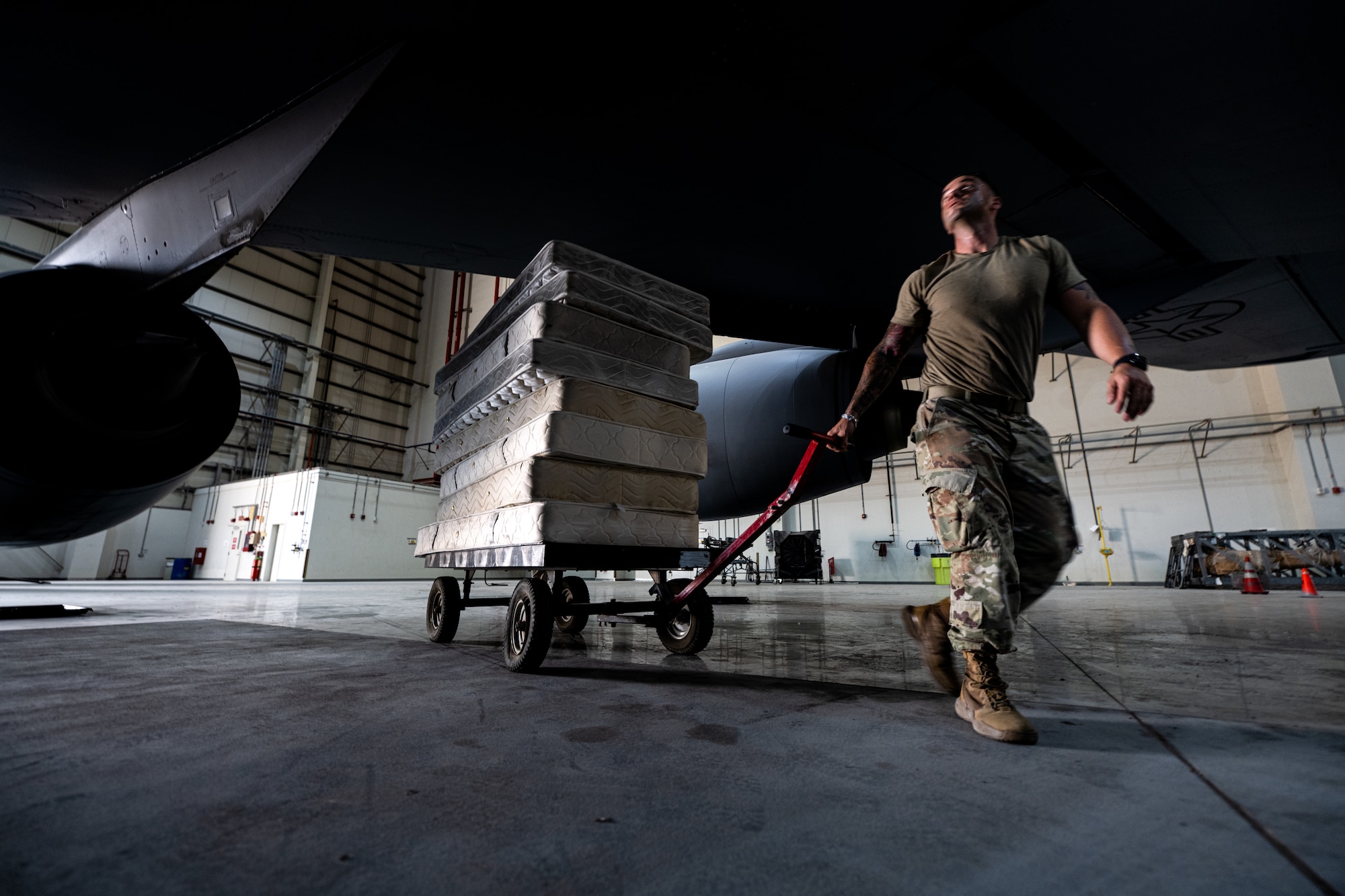 Airman wheeling out a stack of mattresses