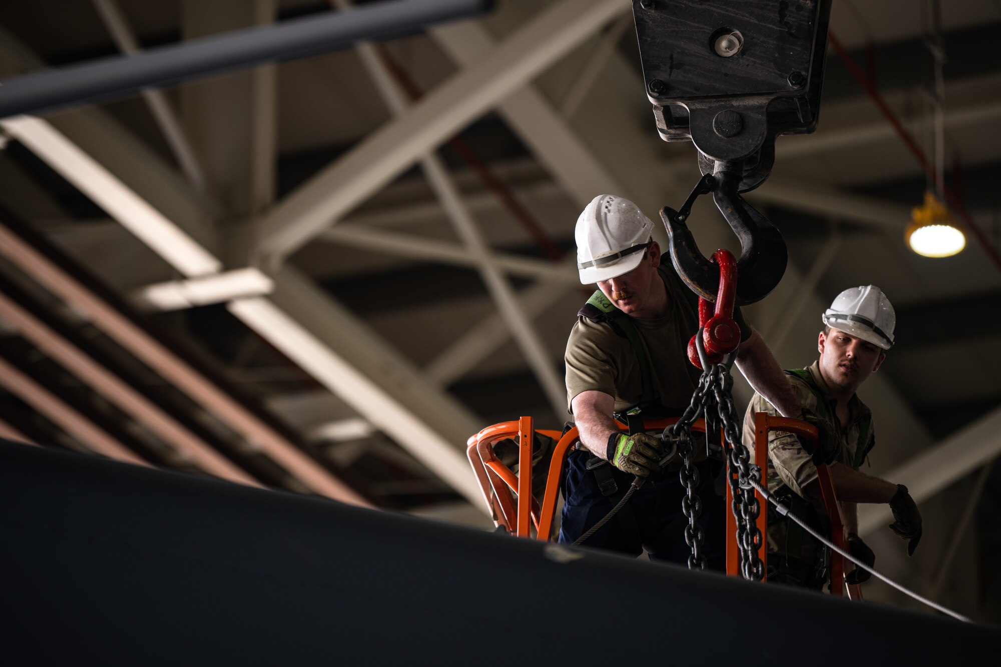 Airmen latching a crane to an aircraft fin