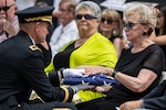 Soldier handing a folded flag to a woman.