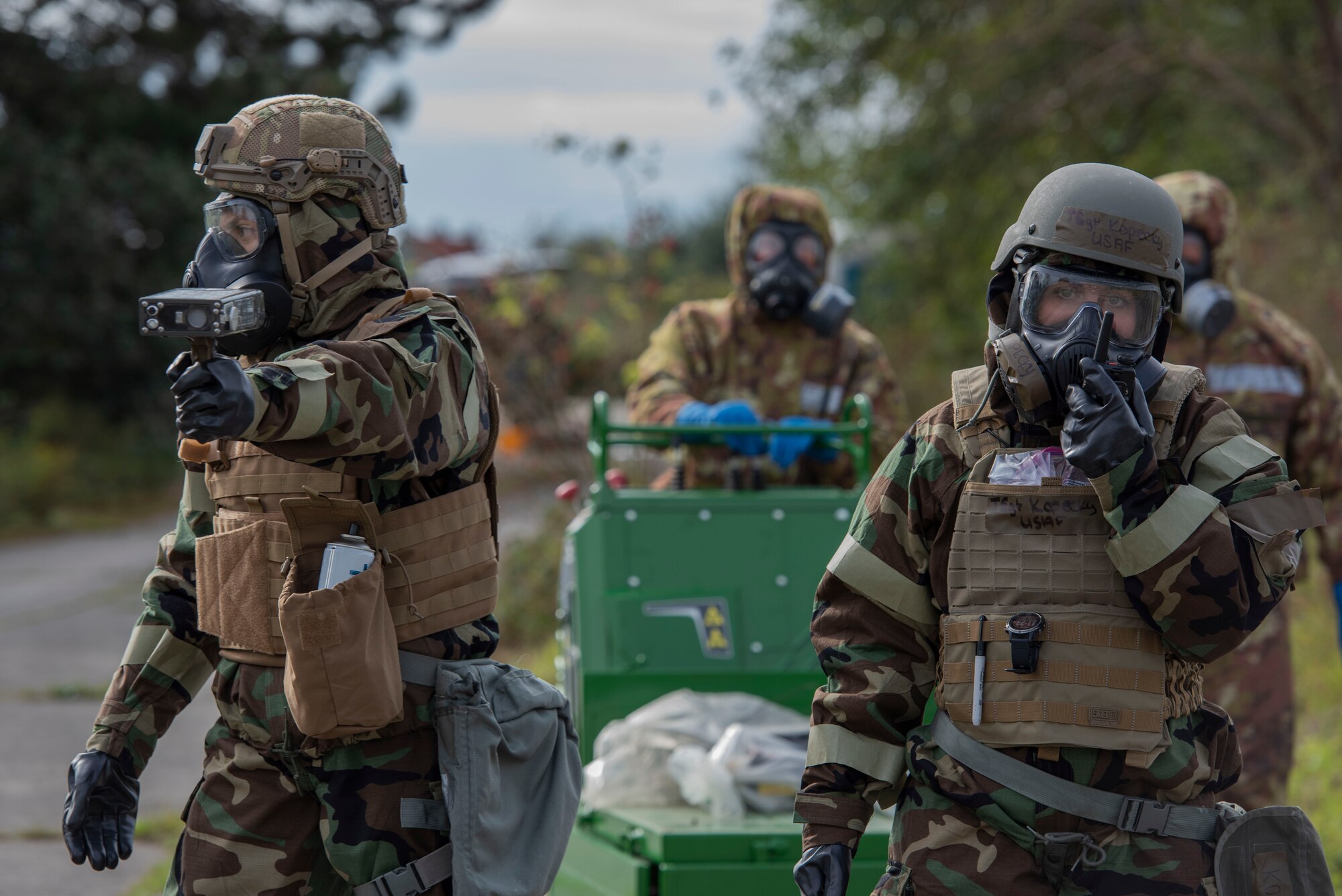 An airman scans for radiation while another airman uses a radio