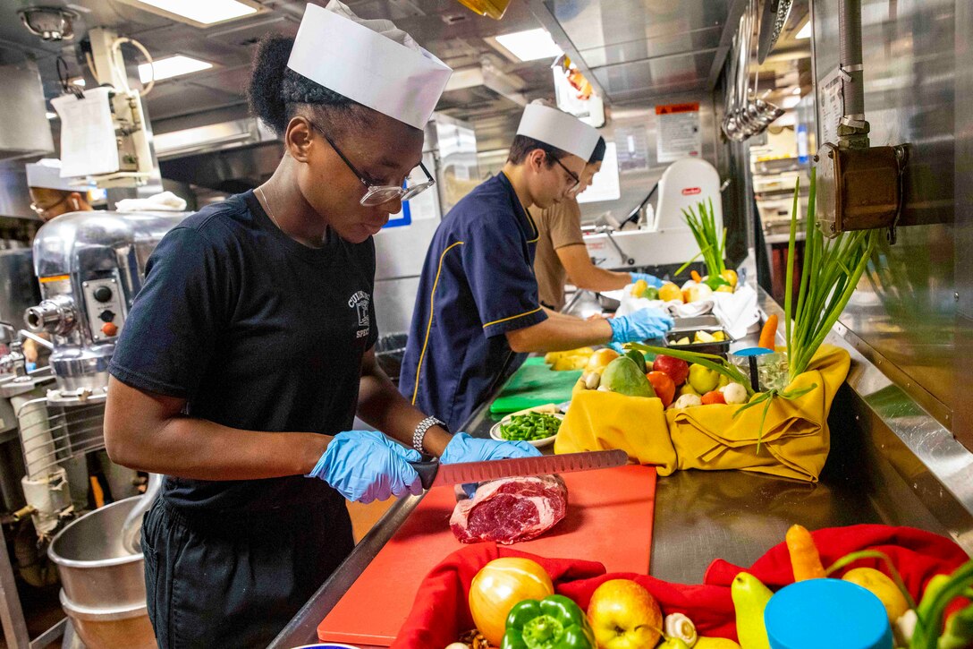 Three sailors prepare food.