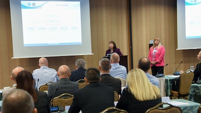 two women talk from a podium in front of an audience