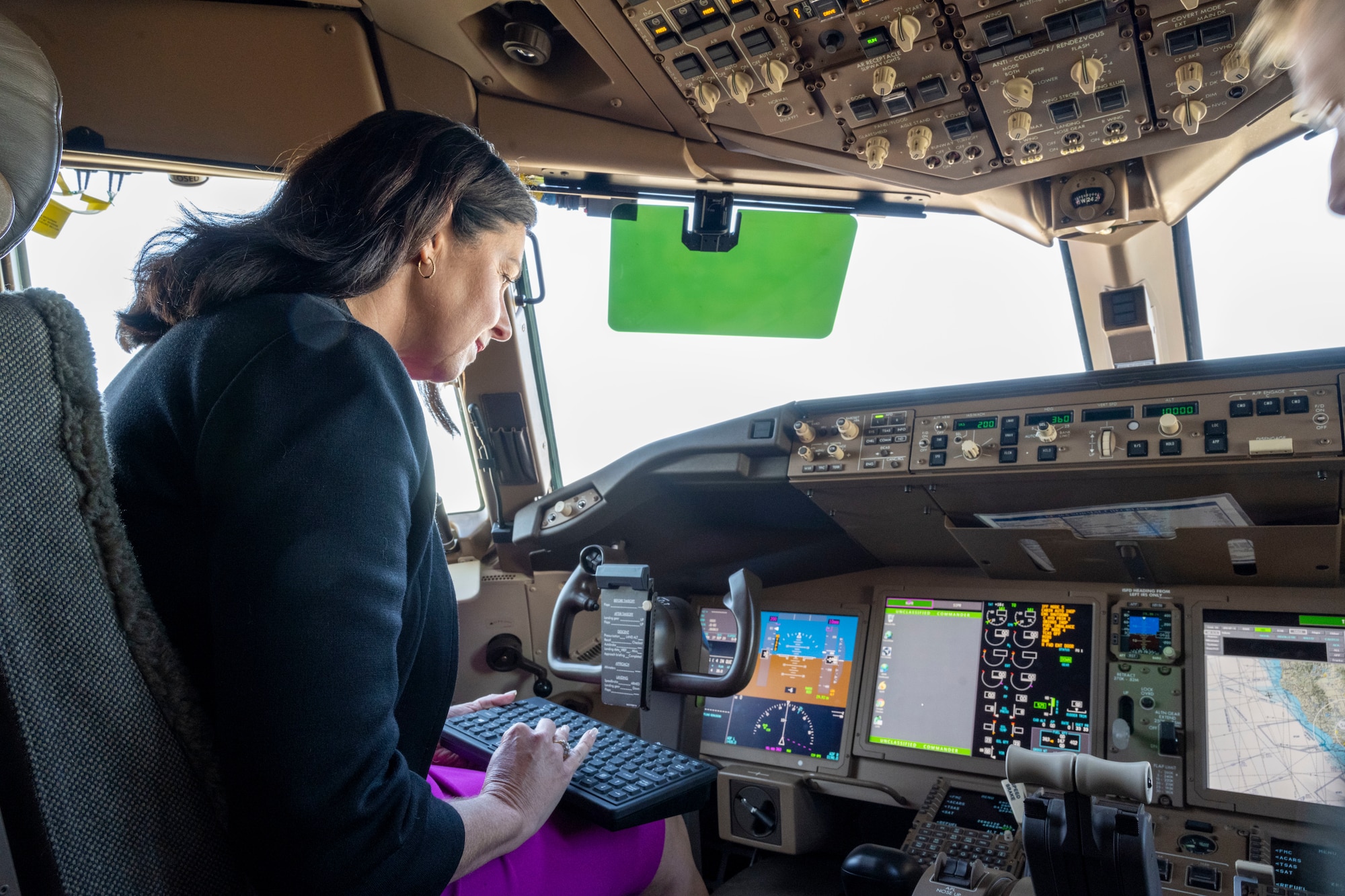 Woman uses computer in aircraft flight deck.