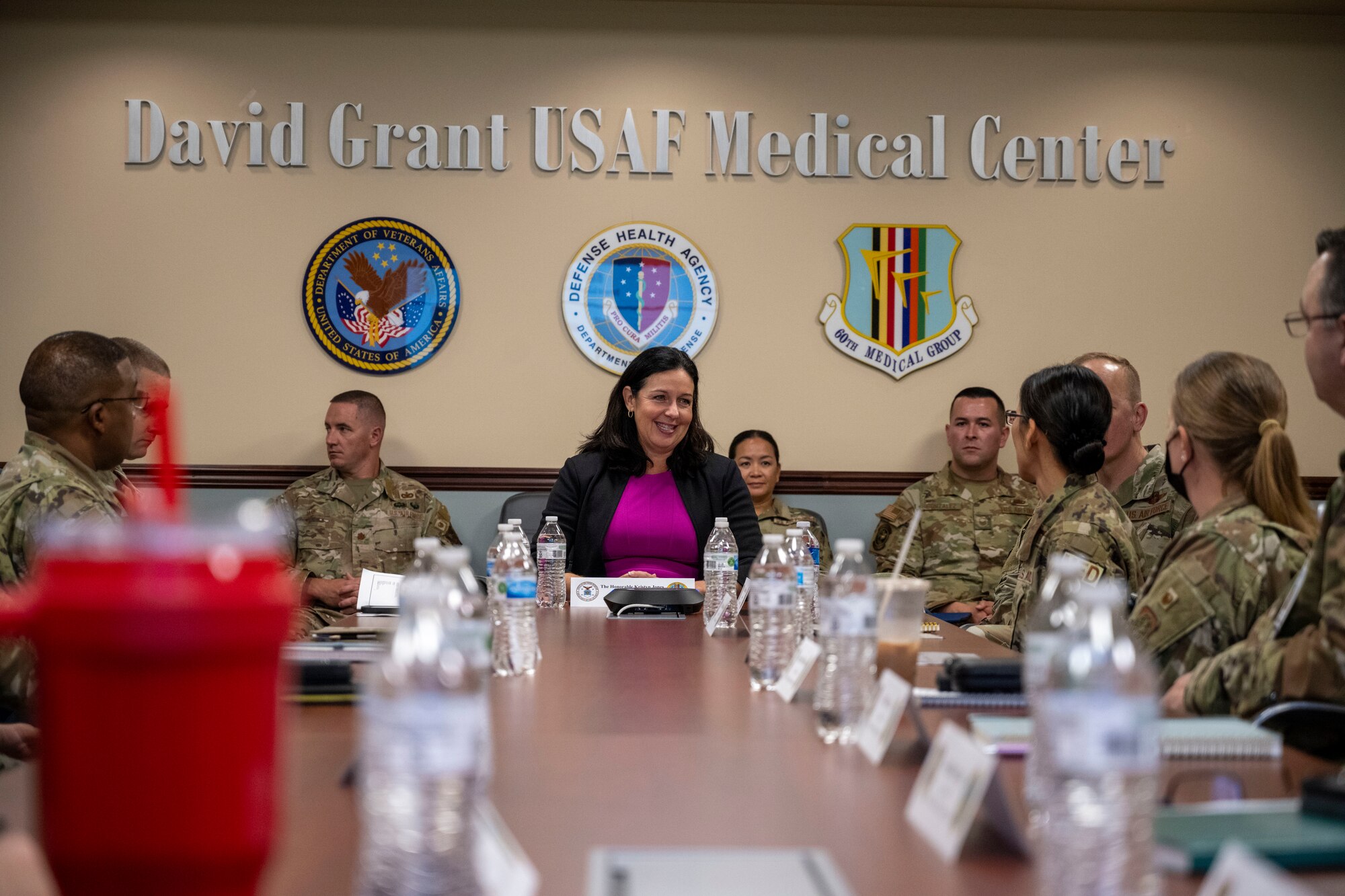 Woman sits at conference table.