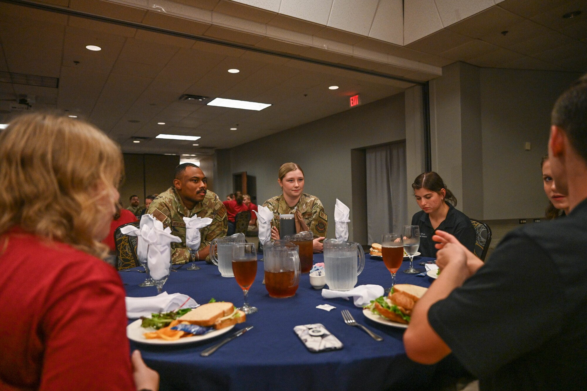 People in uniform share a meal with high school students