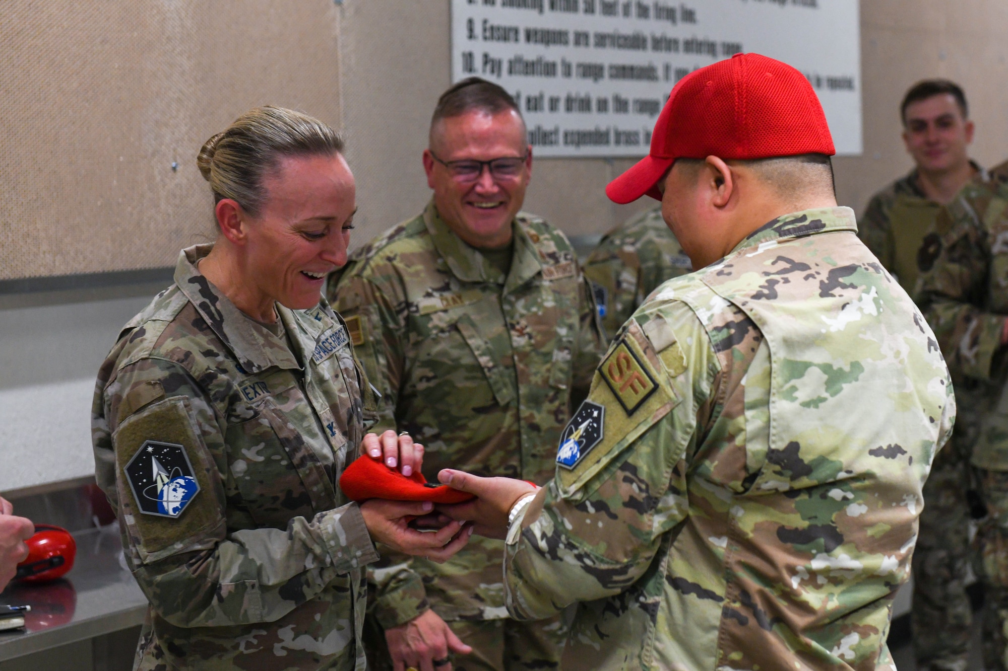 A woman takes a red beanie out of a man's hand.