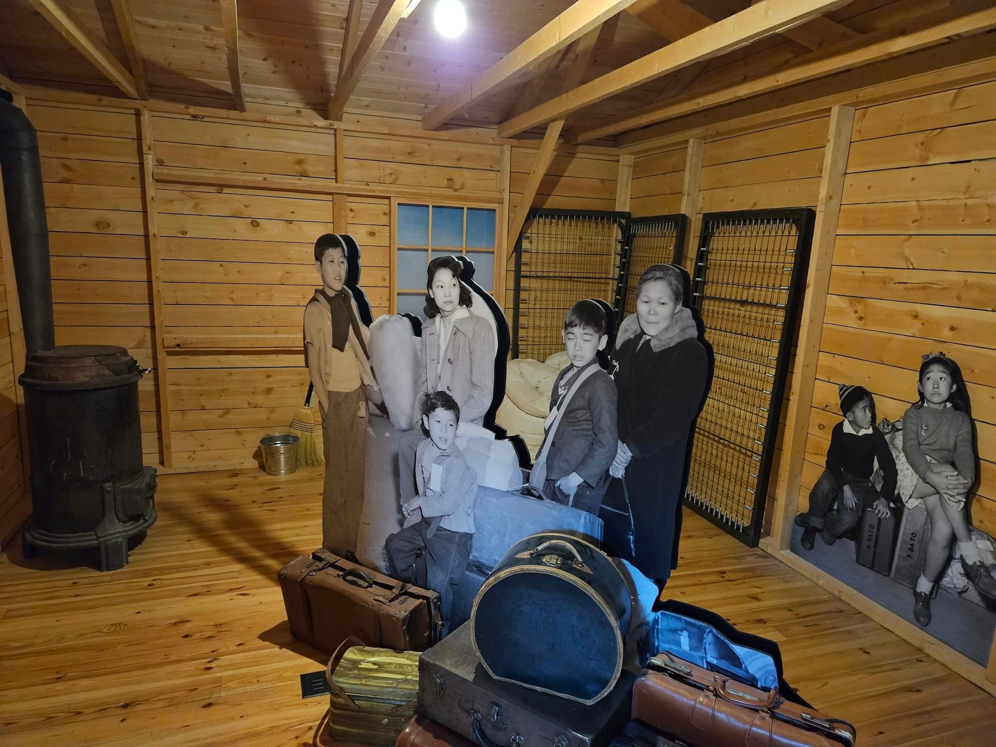 cardboard cut outs of a Japanese American family standing in what would be an allotted room at Heart Mountain internment camp