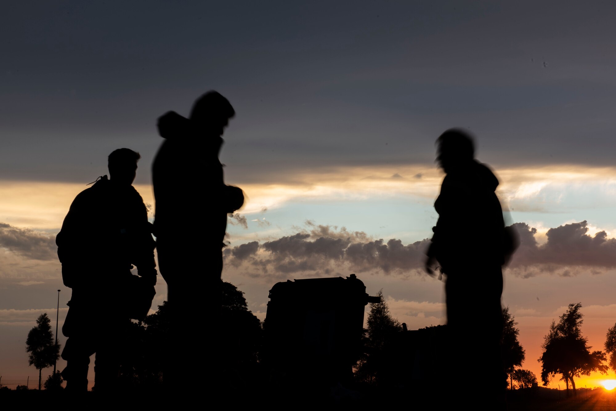 Three people set up a decon line at sunset