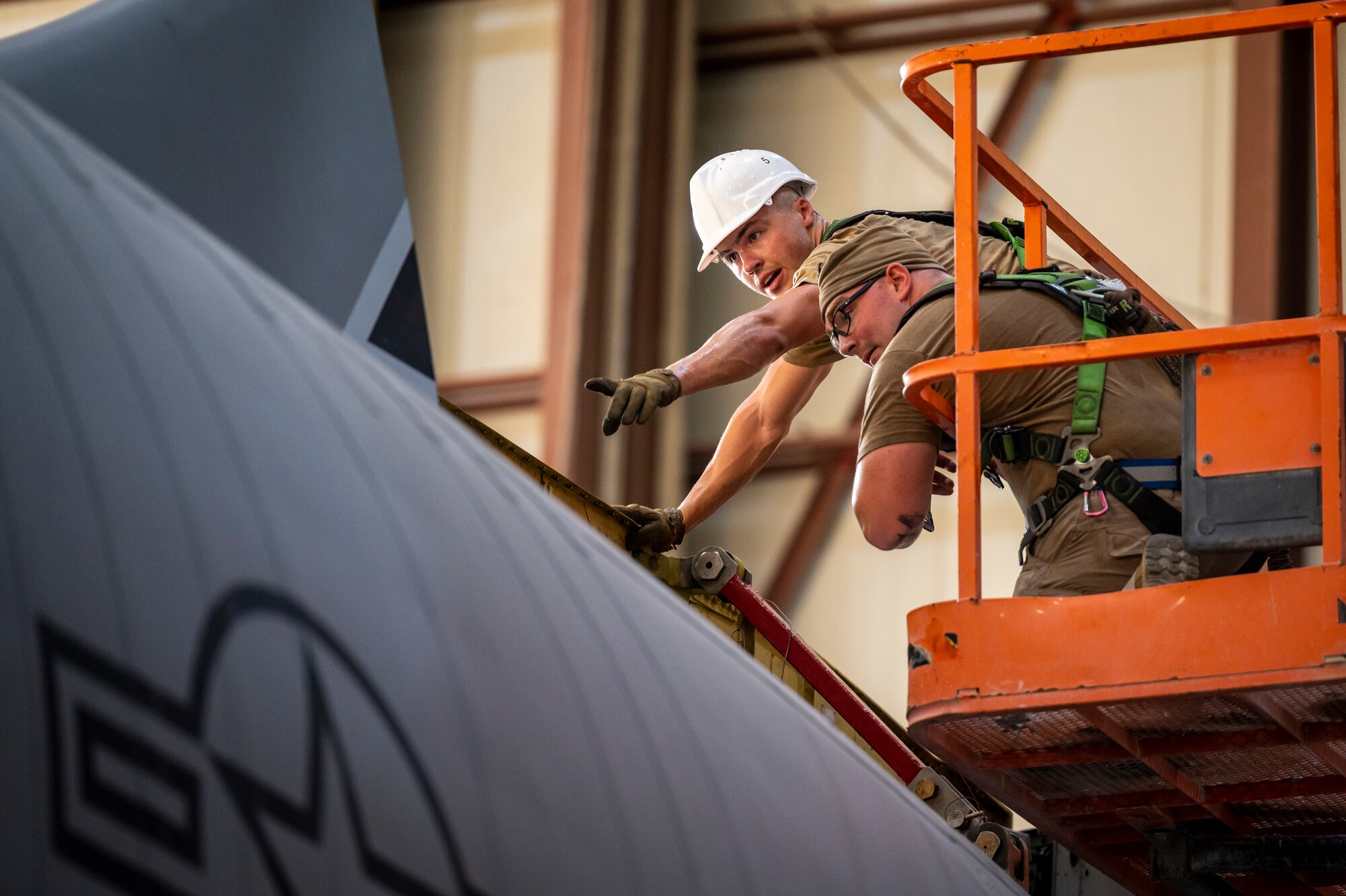 Airmen on a lift next to an aircraft