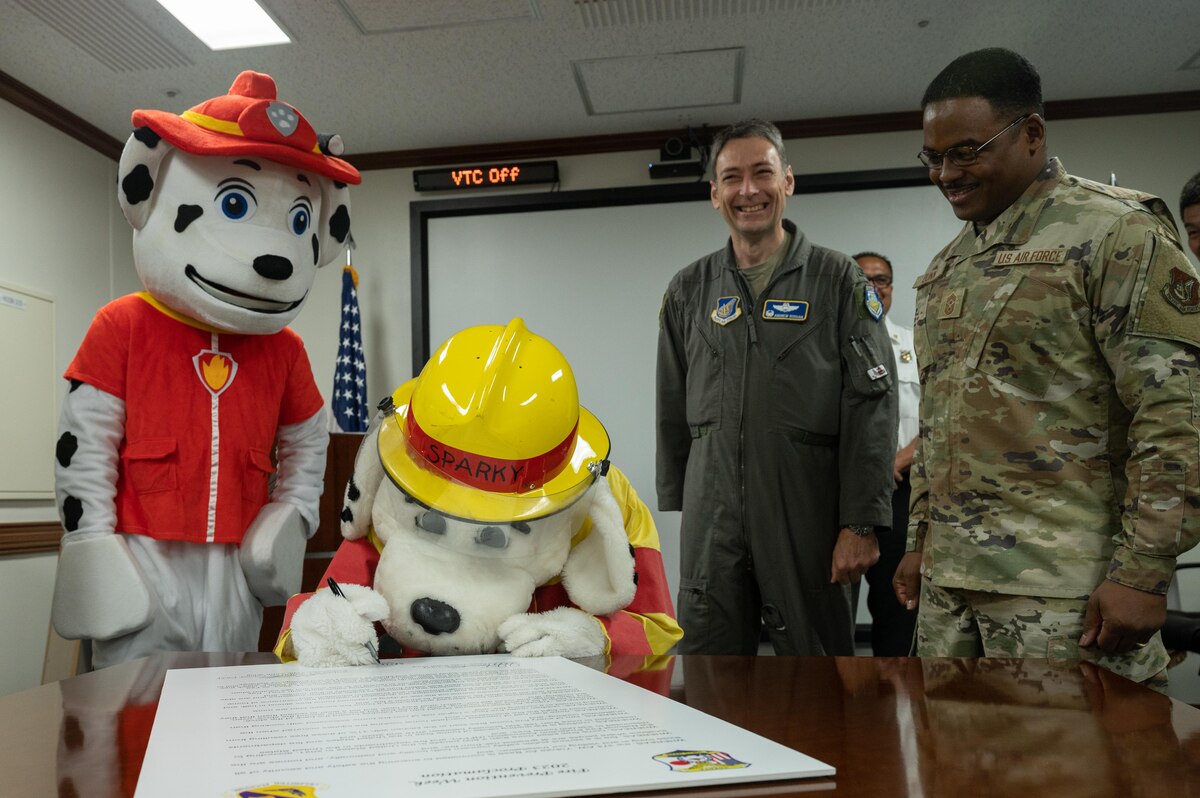 Sparky the Dog signs a proclamation for Fire Prevention Week.