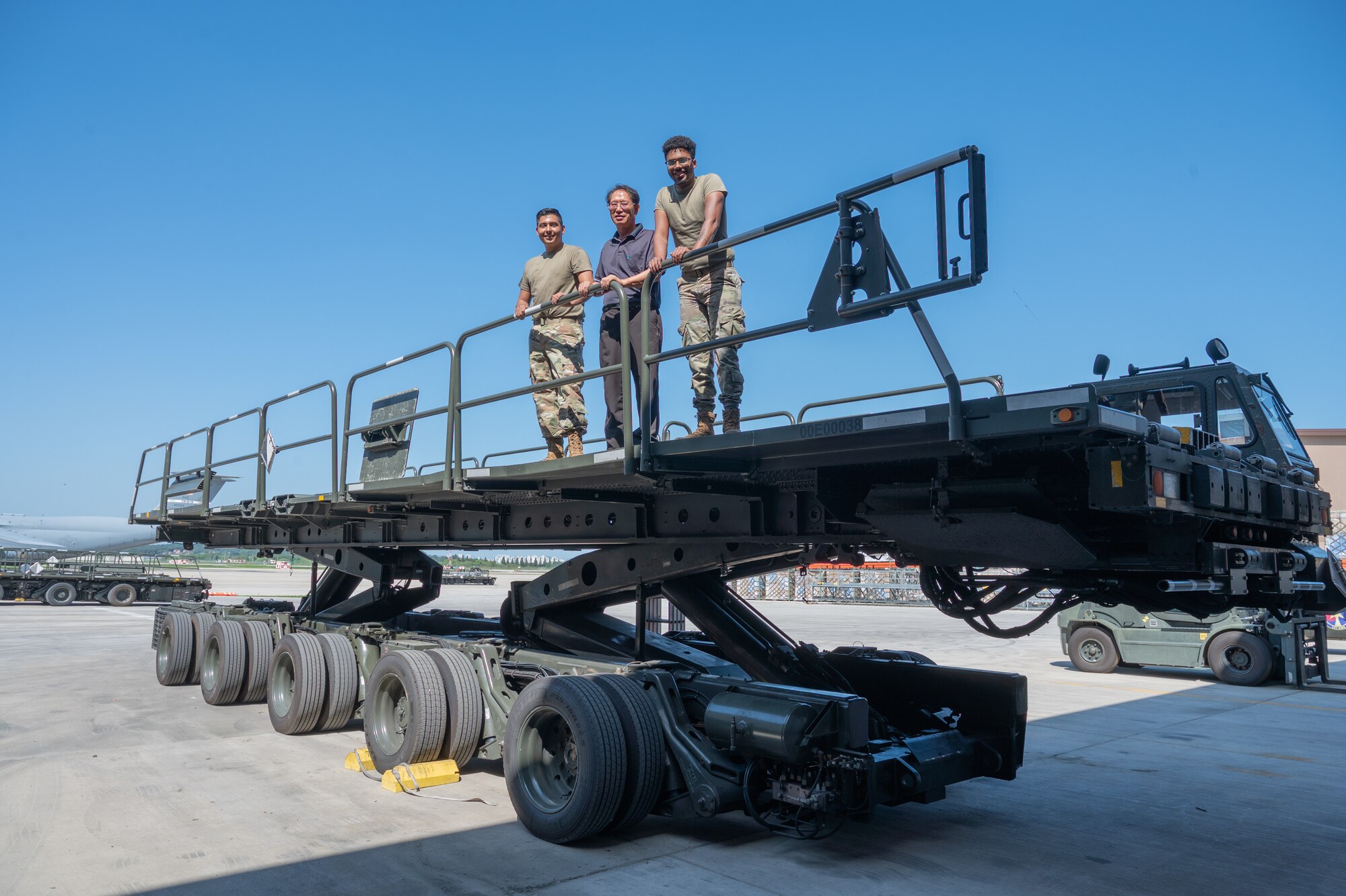 From the left, U.S. Air Force Staff Sgt. John Bello, Yi San Young, and Senior Airman Dillion Evans, 51st Logistics Readiness Squadron material handling equipment maintainers, pose for a photo at Osan Air Base, Republic of Korea, Sept. 8, 2023. The vehicle validation process ensures equipment like an aircraft loader and transporter, is being utilized for its purpose and remains within Air Force standards to ensure mission readiness of the 51st Fighter Wing. (U.S. Air Force photo by Staff Sgt. Kelsea Caballero)