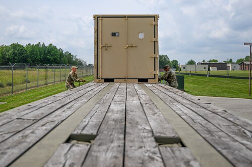 Senior Airman Aaron Razayeski, a Consolidated Asset Management Site ground transport specialist for the Innovative Readiness Training program, and Master Sgt. Daniel Payne, the CAMS warehouse manager for IRT, load a container onto a tractor-trailer, July 28, 2023, at Youngstown Air Reserve Station, Ohio. Razayeski and Payne trucked over 1,000 miles one-way to Monroe and West Monroe, Louisiana, in support of Monroe Wellness 2023. (U.S. Air Force photo by Eric M. White)