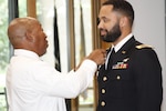 Army 1st Lt. Demetre Harris has his branch insignia pinned on his uniform by his father as part of the graduation ceremony for the Interservice Physician Assistant Program on Sept. 29 at Walter Reed National Military Medical Center.