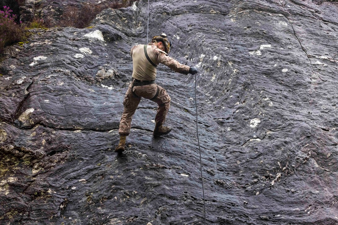A Marine descends a rock face.