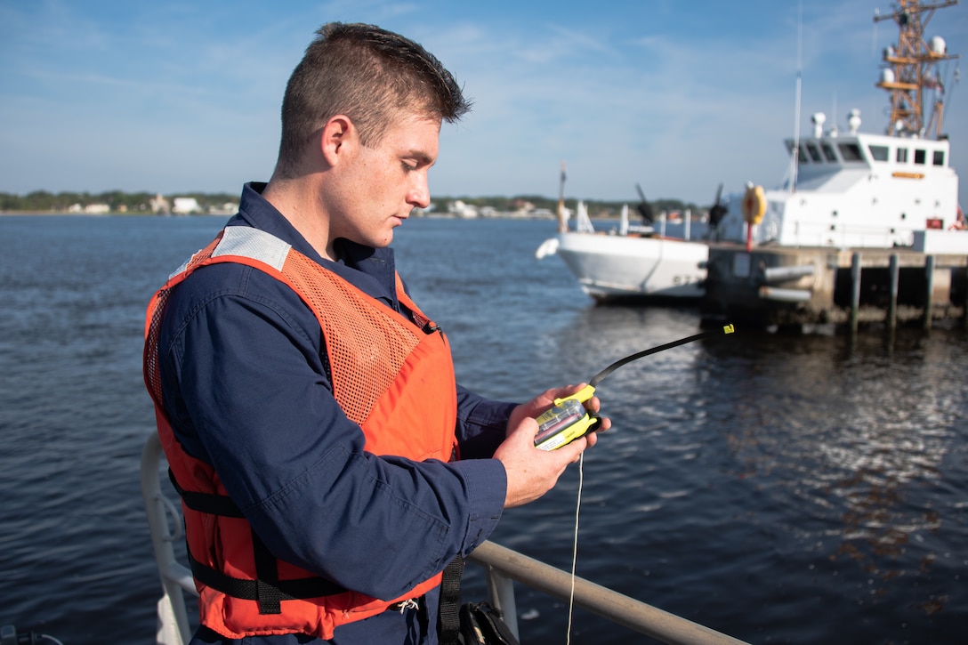 Petty Officer 3rd Class Benjamin Mullis, a coxswain from Coast Guard Station Mayport, demonstrates how to use a personal locator beacon (PLB) in Mayport, Florida, Sep. 30, 2020. Boaters should have an emergency position-indicating radio beacon (EPIRB) or a personal locator beacon (PLB) on-board to send a distress signal on the 406 MHz distress frequency via satellite and earth stations to the nearest Rescue Coordination Center, which then notifies local Search and Rescue assets.