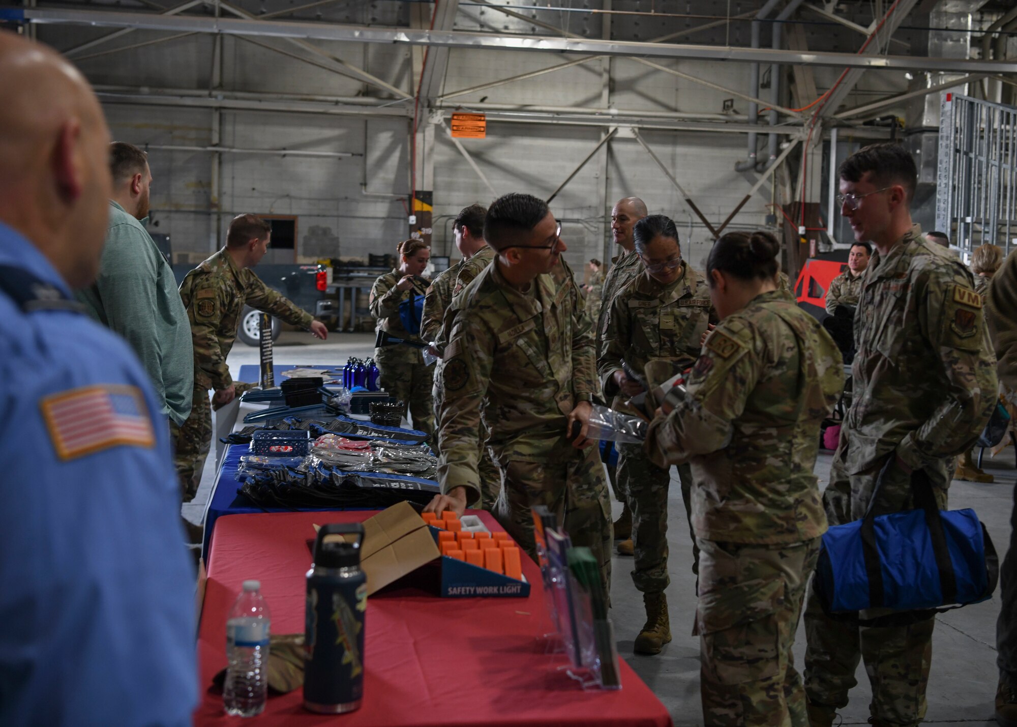 People in green uniforms stand around table filled with objects.