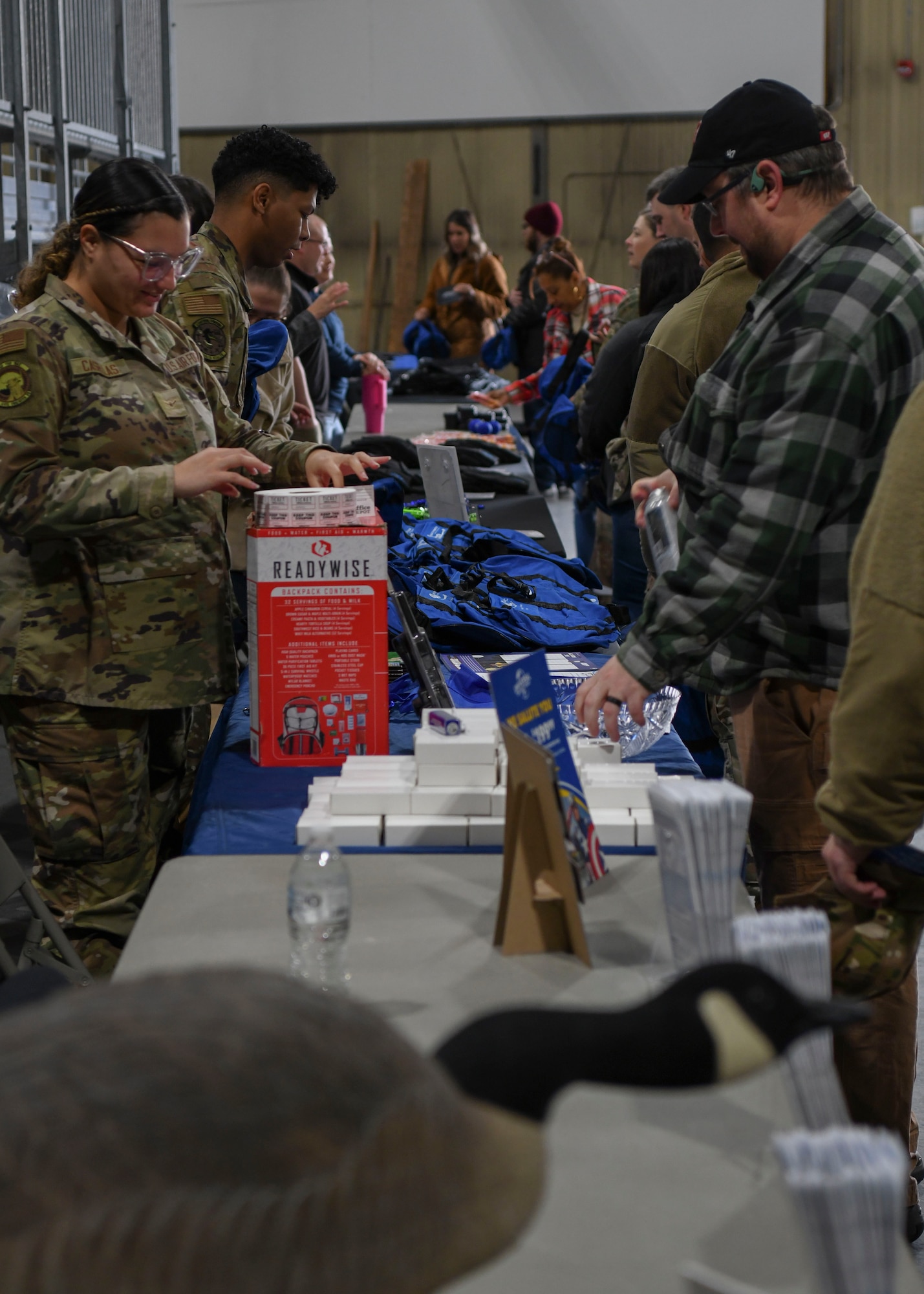 People stand around table filled with objects.