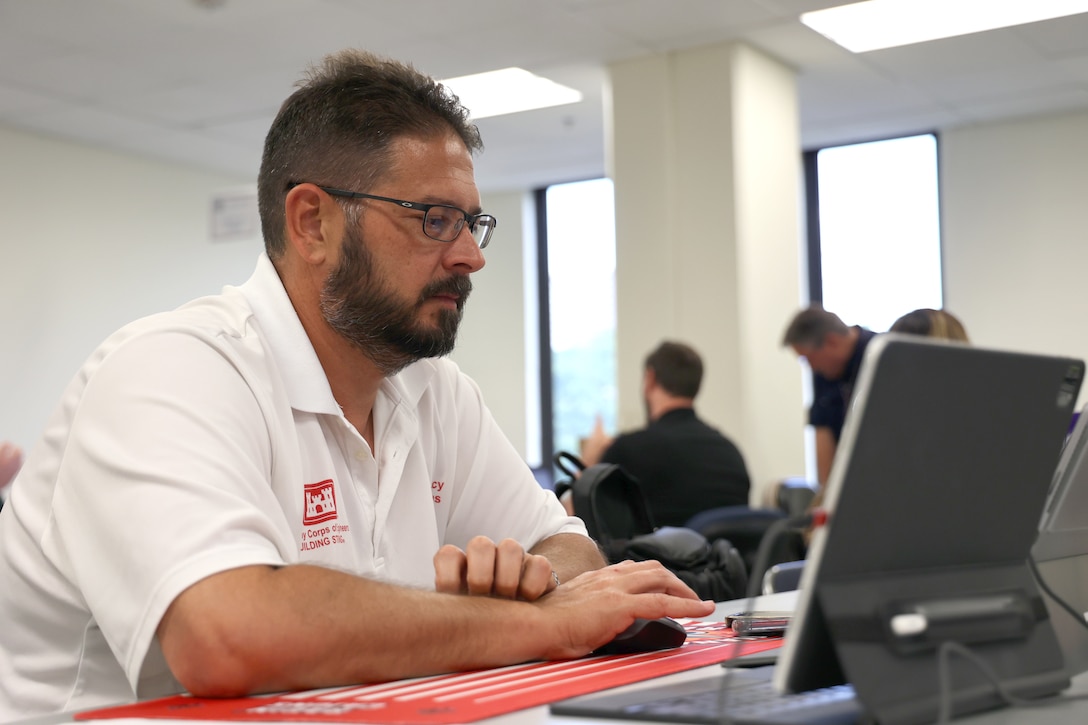 A man sits and works at a tablet computer.