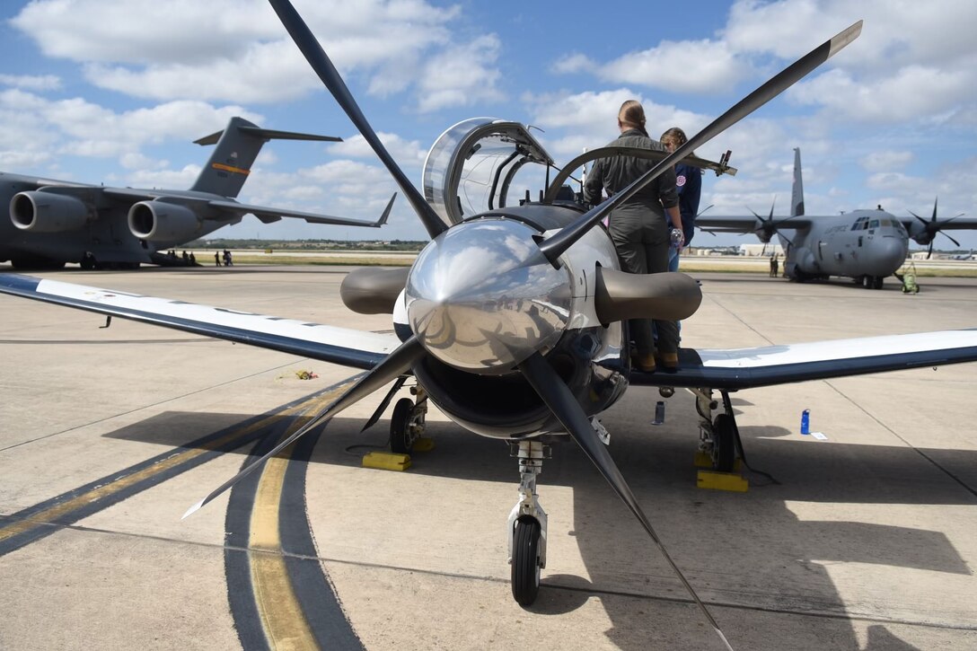 The front view of a T-6 Texan II with a pilot showing a woman the interior.