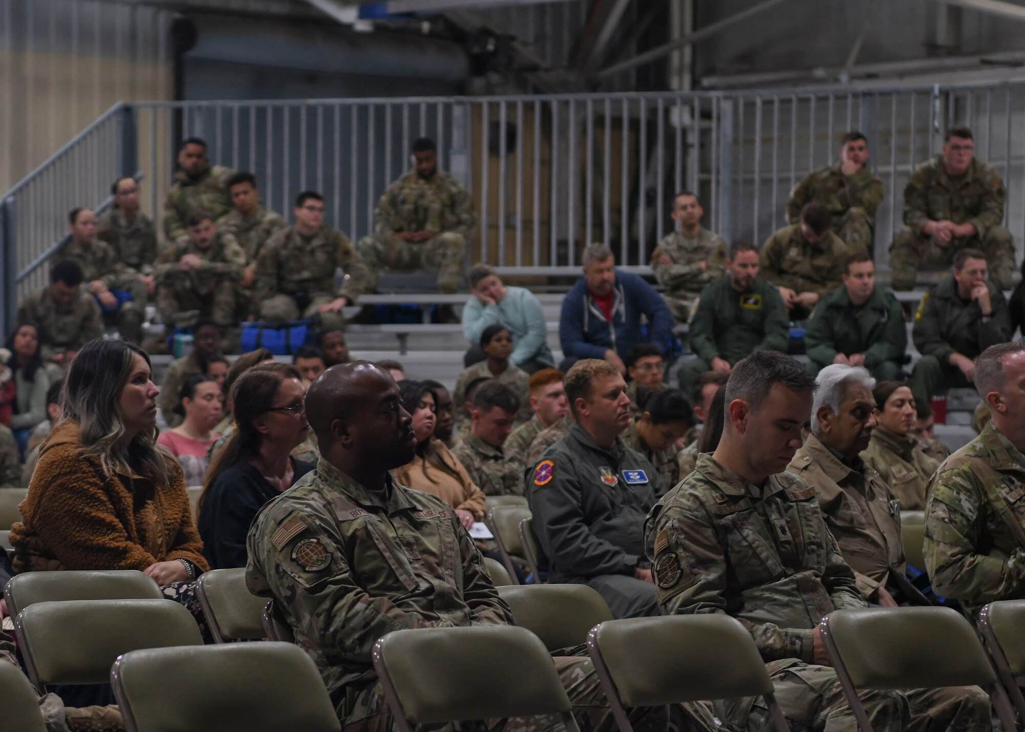 People in green uniforms sit and watch a presentation.