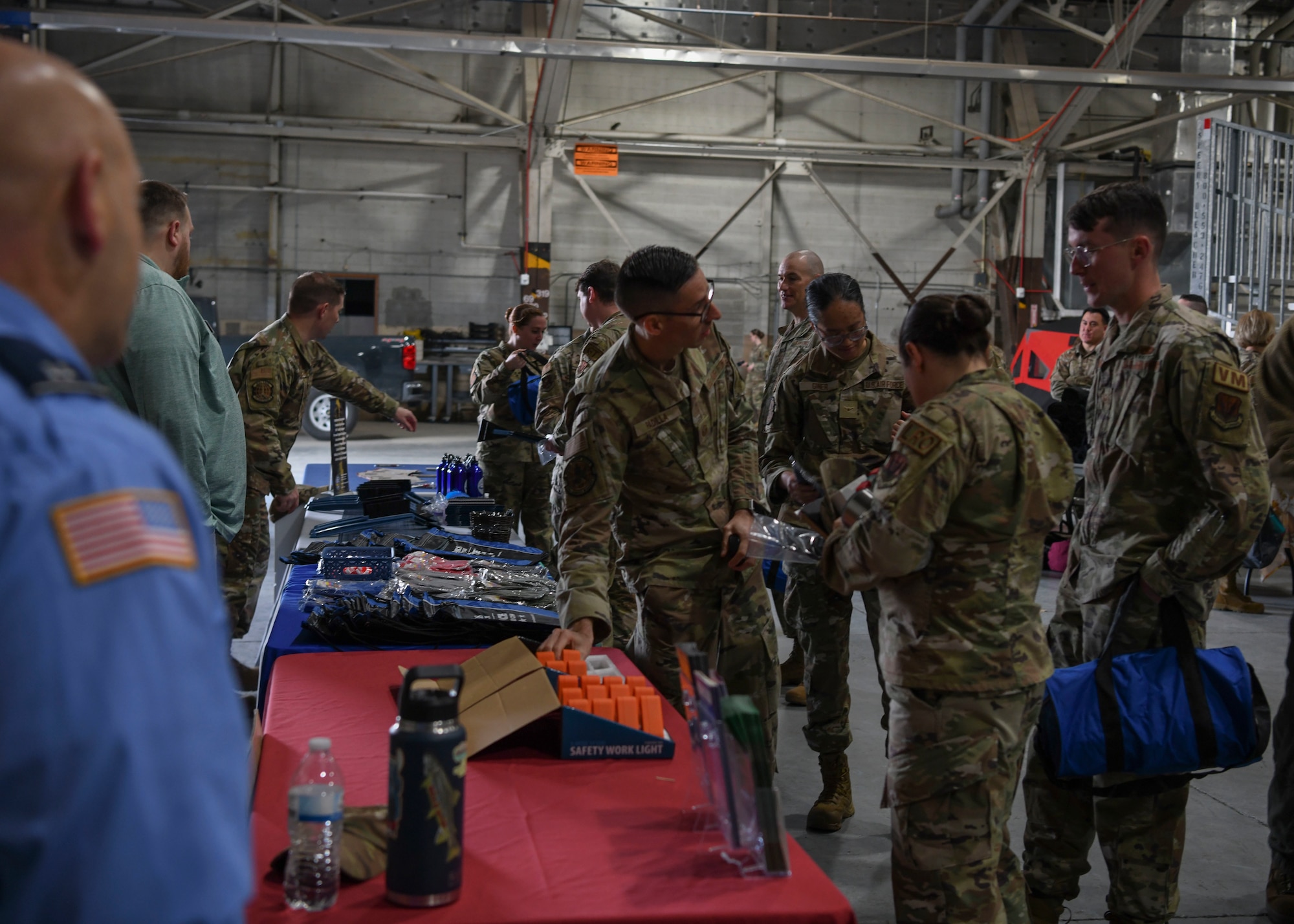 People in green uniforms stand around table filled with objects.