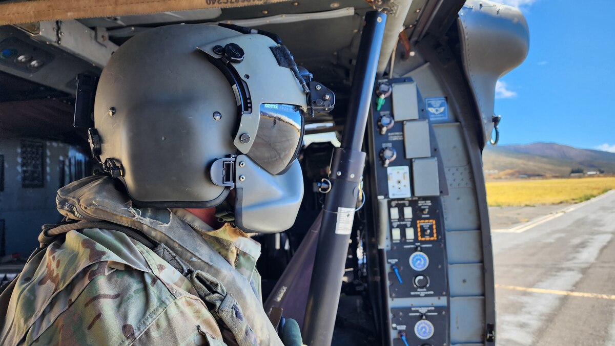 Army crew chief watches two Air Force Reserve members walk away from helicopter.