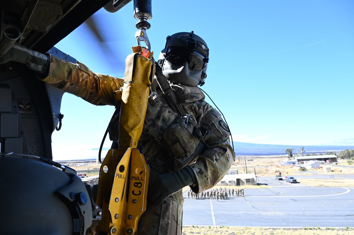 Army flight paramedic is lowered to ground during hoist training.