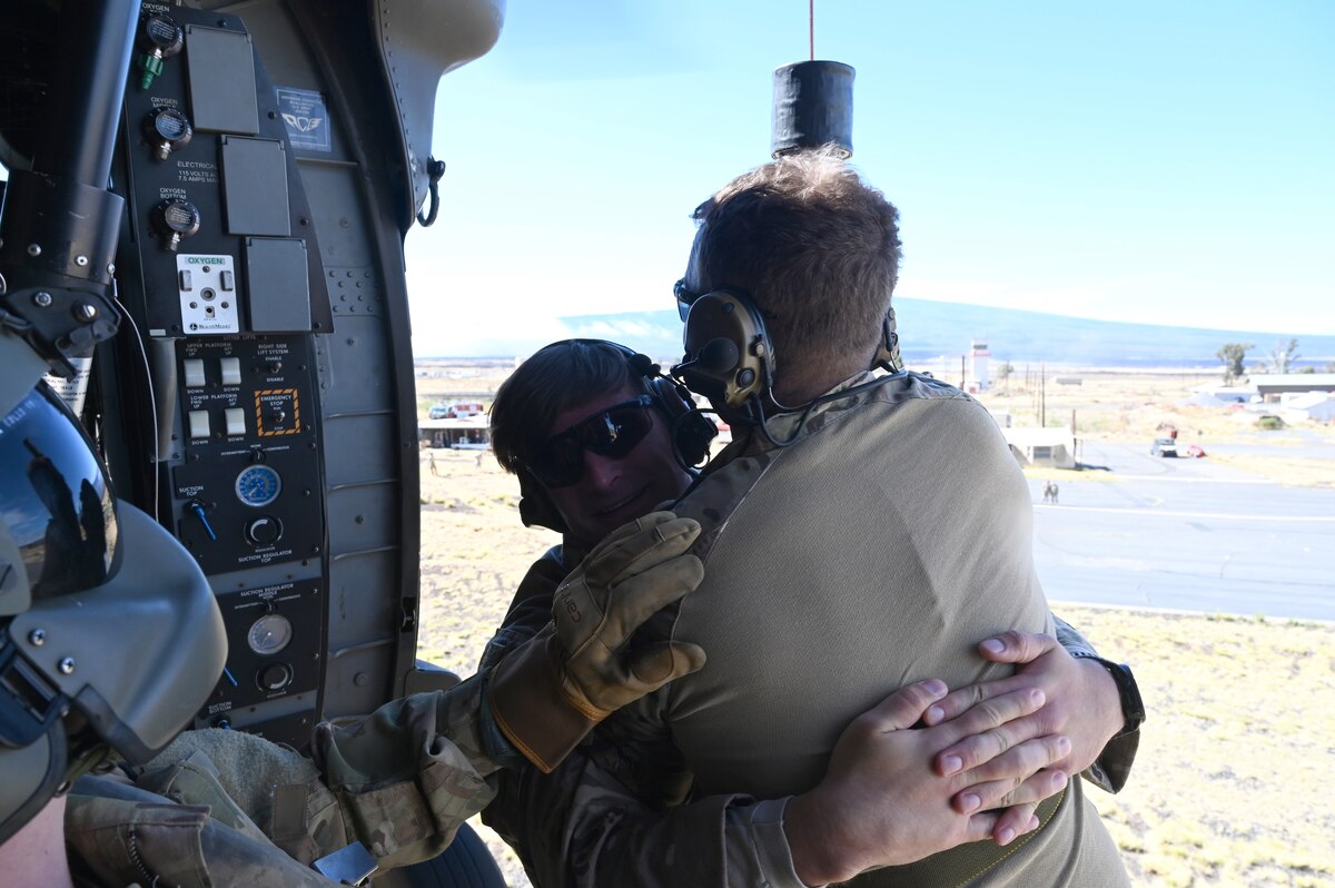 Army crew chief receives two Air Force Reserve members on hoist during training.
