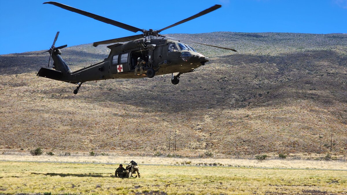 Air Force Reserve Airmen are lifted on a hoist up by an Army HH60-M Black Hawk medical evacuation (MEDEVAC) helicopter.