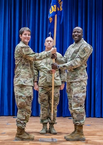 U.S. Air Force Col. Julie Gaulin, 386th Air Expeditionary Wing commander, passes the guidon to Col. Adeleke Ekundayo, incoming 386th Expeditionary Air Base Group commander, during an assumption of command ceremony at Ali Al Salem Air Base, Kuwait, Oct. 3, 2023.