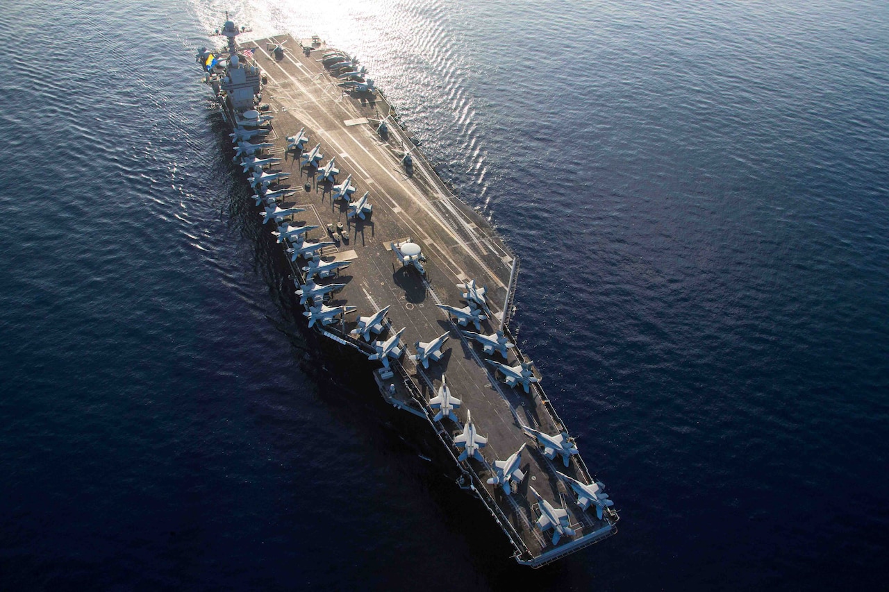 Aerial view of aircraft carrier at sea with aircraft on flight deck.