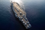 Aerial view of aircraft carrier at sea with aircraft on flight deck.