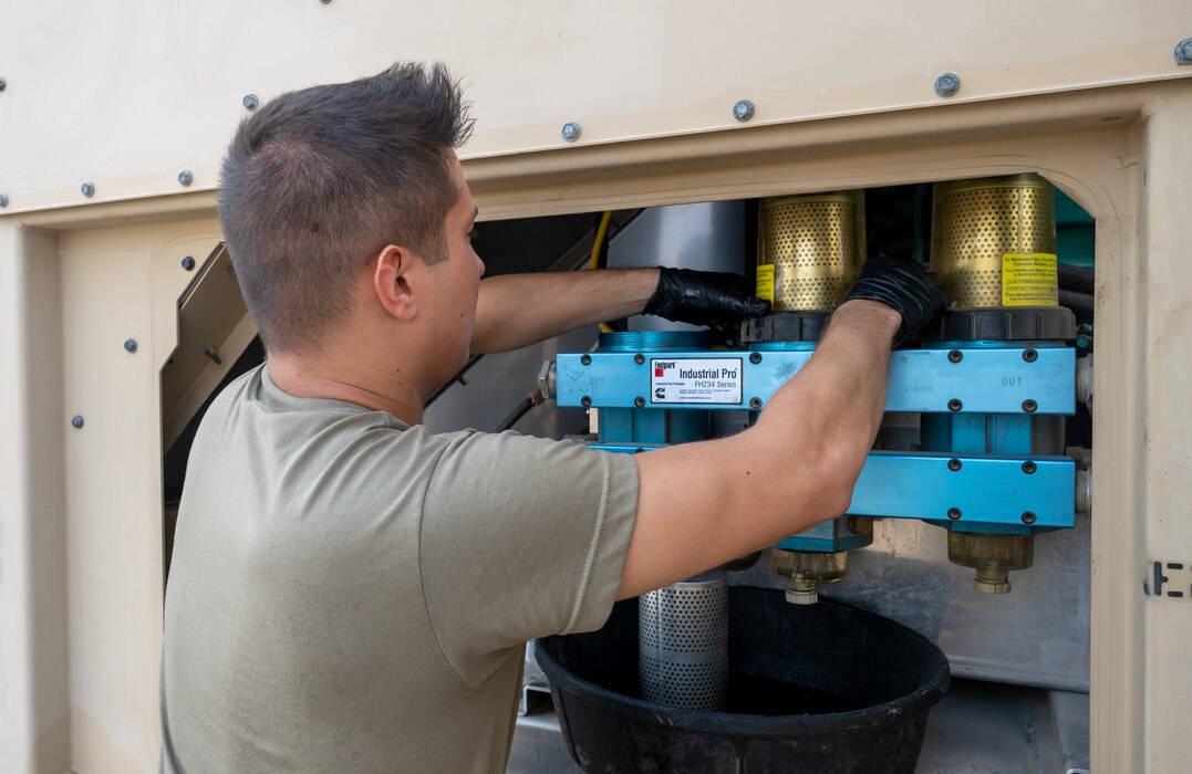 A photo of an Airman replacing a filter on a generator.