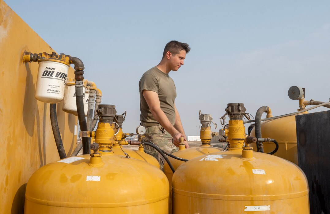 A photo of an Airman standing by several tanks.