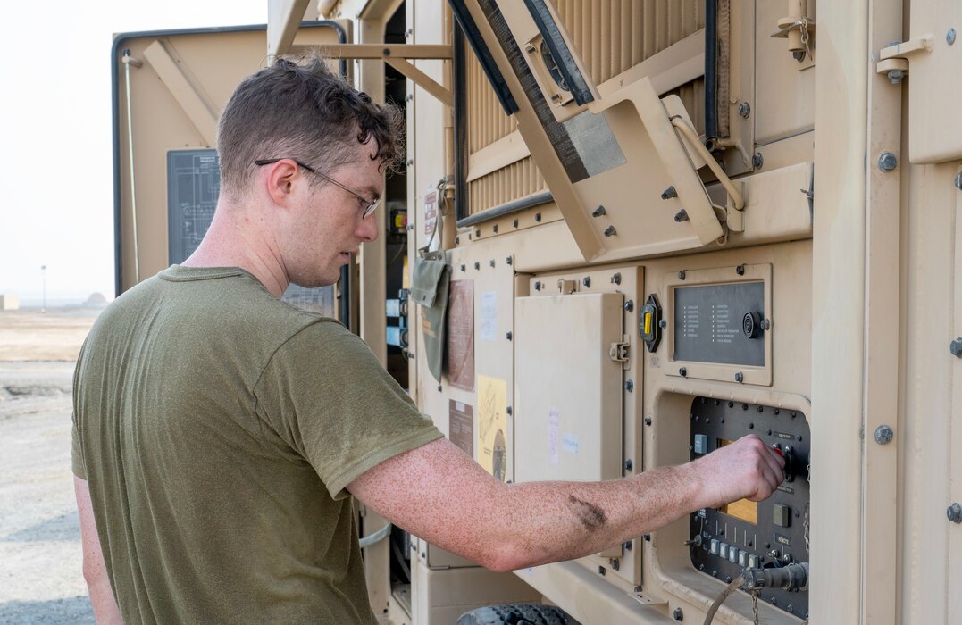 A photo of an Airman pressing a button on a generator.
