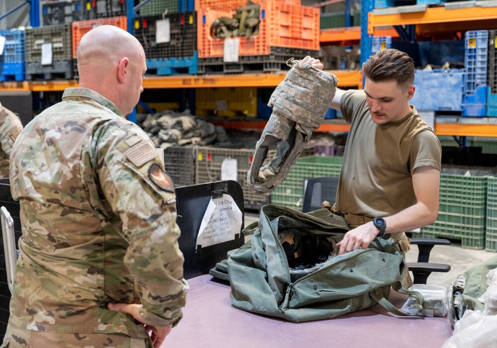 A photo of an Airman removing a plate carrier from a bag.
